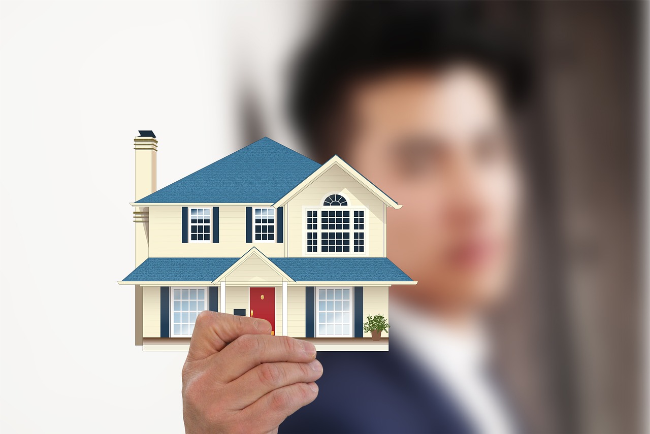 Person holding a model house, symbolising real estate investment or homeownership